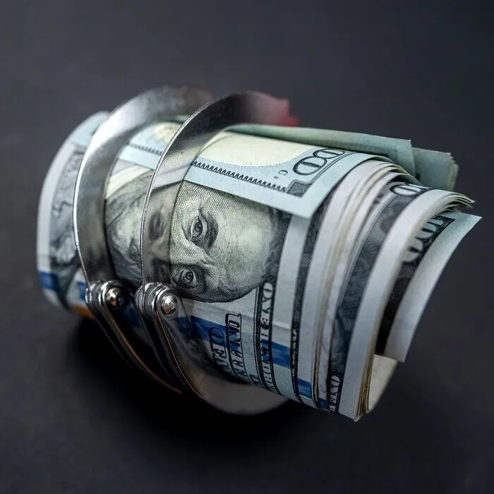 Police handcuffs lie on many dollar bills