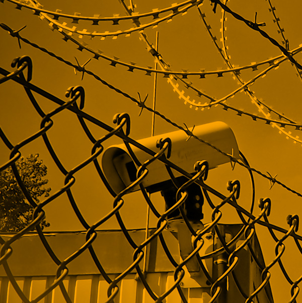 yellow duotone of chain link fence, surveillance camera and barbed wire fence