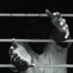 Hands reaching through prison bars