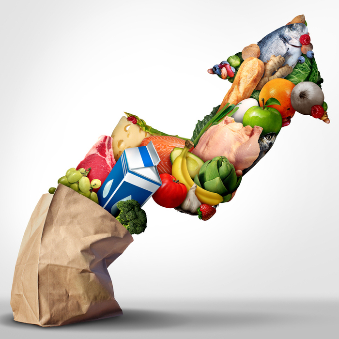 Upward-pointing arrow ascending out of a paper bag, made up of grocery items