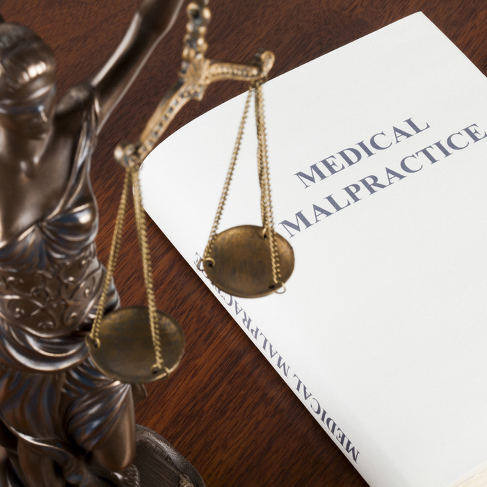 A report titled medical malpractice next to a statue of lady justice