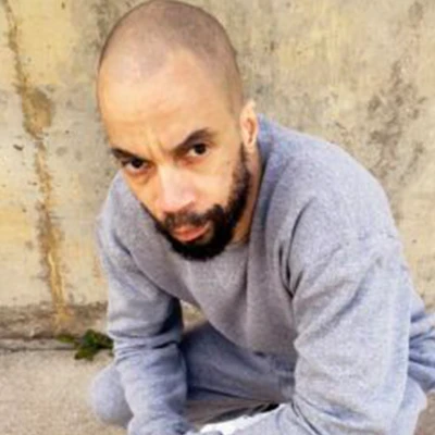 Man with shaved head and beard kneeling