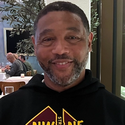 rob-2 Black man with short hair and beard wearing a DC sweatshirt sitting in a restaurant smiling.