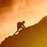Man climbing up mountain cliff. Working hard to reach goals