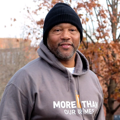 Smiling Black man with black knit cap and More Than Our Crimes sweatshirt